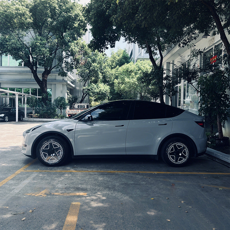 White Tesla Model Y with pentagon-pattern wheel covers, a budget-friendly wheel upgrade
