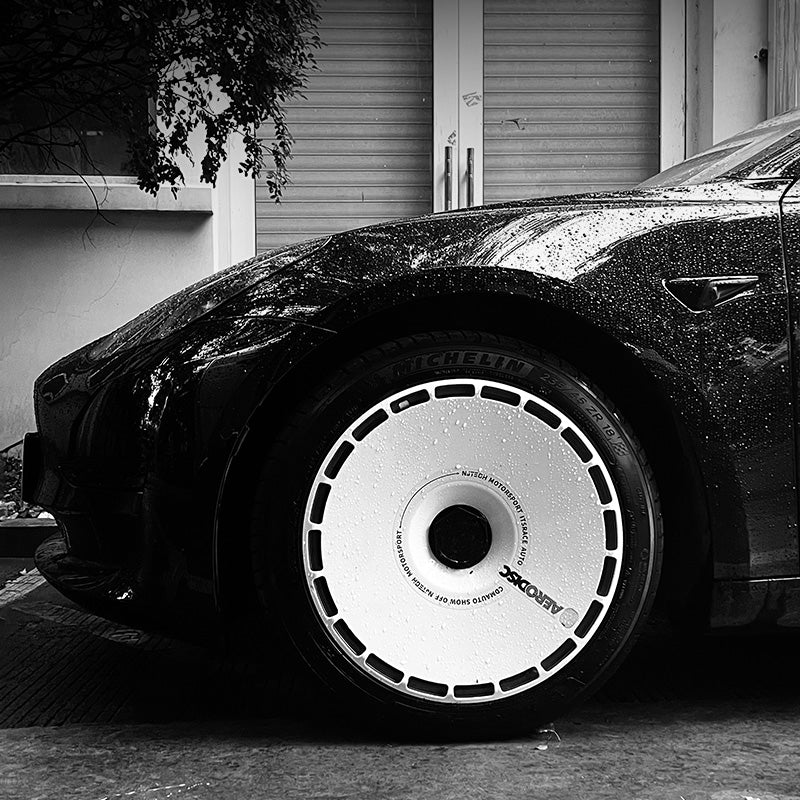 Close-up of a white aero wheel cover on a black Tesla, built to reduce drag at high speed
