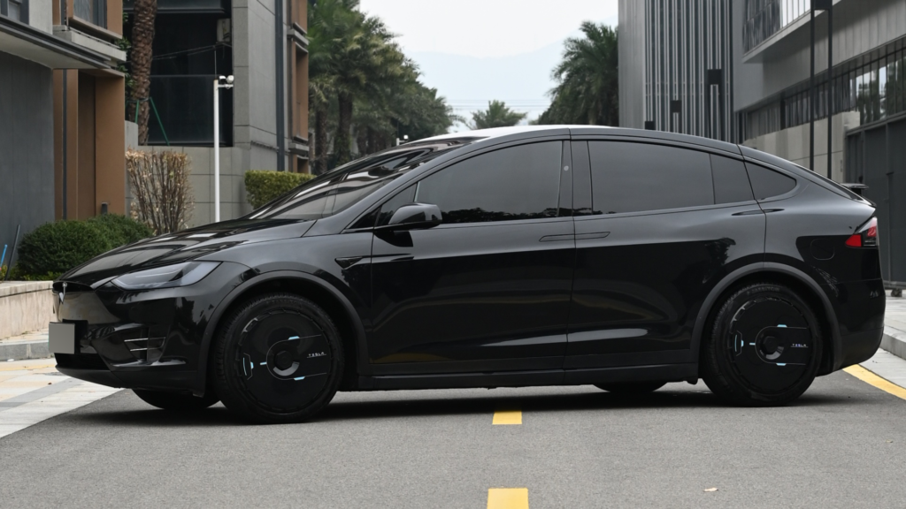 Can you drive a Tesla without wheel covers? Black Tesla with aero wheel covers on a city street