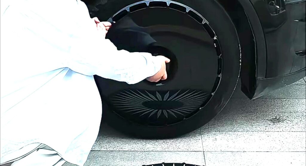 Tesla wheel cover clips being pressed into place on a black Model Y wheel