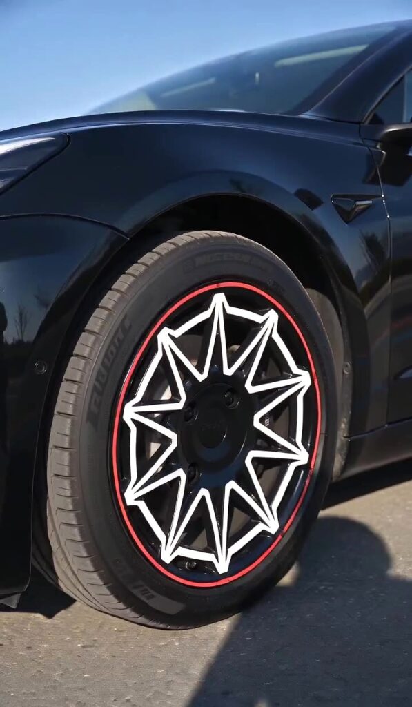 Tesla Model 3 Performance wheel covers with black star-pattern design and red pinstripe accents